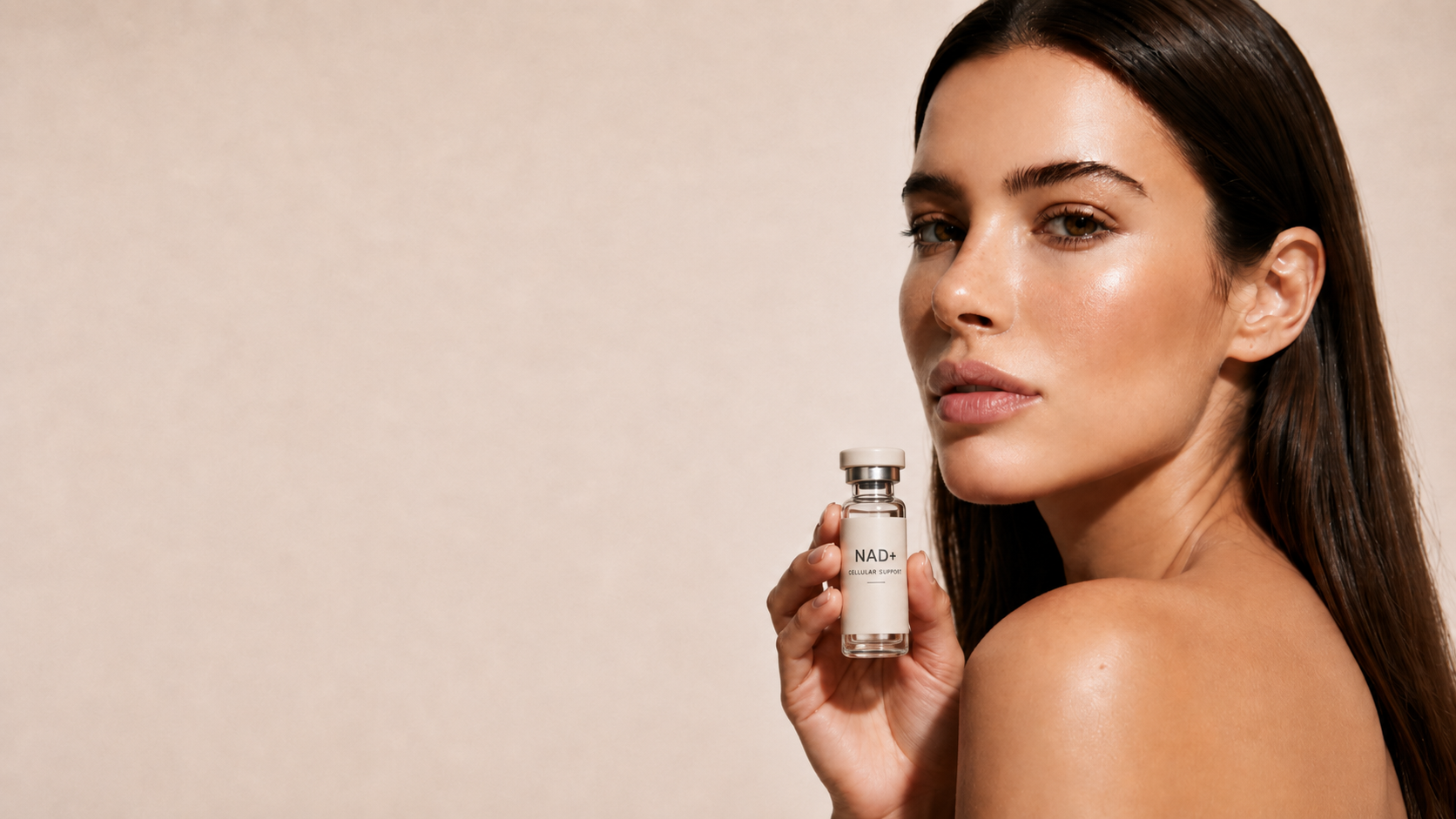 Woman holding an Aure NAD+ vial against a warm neutral backdrop